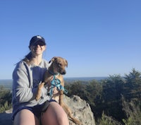 a woman with a dog sitting on top of a rock